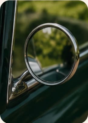 Rétroviseur chromé d’une Mini vert anglais, reflets de vigne dans le miroir.